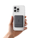 Hand holding a smartphone with a black grip pad on a white background